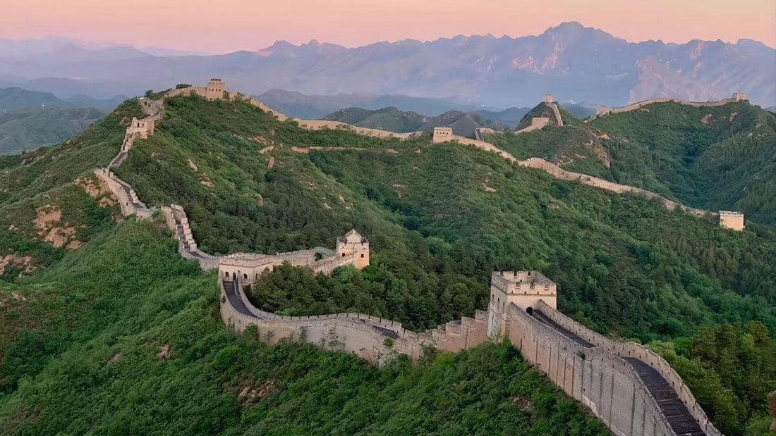 The Great Wall winding across green mountain ridges at sunset