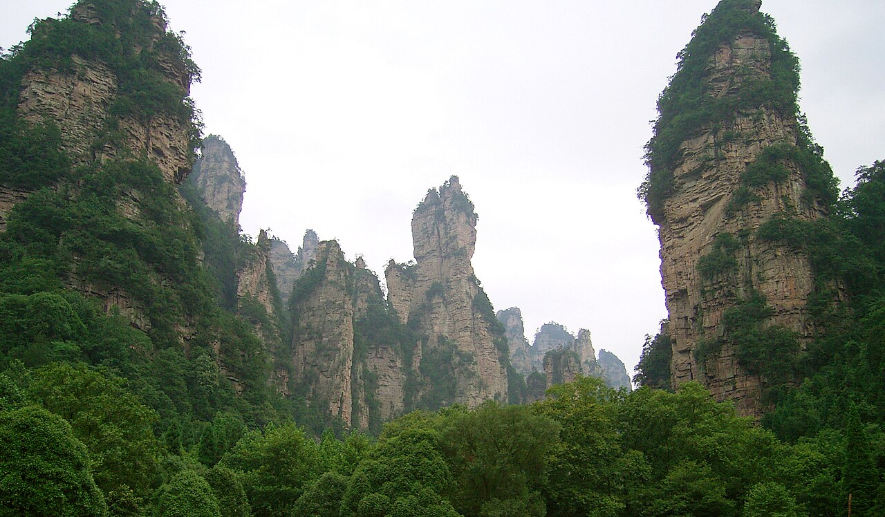 A view from below between the steep rock pillars and green forest of Wulingyuan